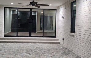 A room with a ceiling fan, a sliding glass door leading to a bathroom, and a tiled floor. - Completely Remodeled, Perfect for the World Cup (Dallas)