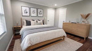A bedroom with a bed, bedside tables, a dresser, and framed wall art. - Completely Remodeled, Perfect for the World Cup (Dallas)