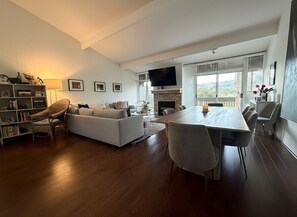 Una sala de estar moderna con sofá, mesa de comedor y sillas, chimenea y televisor.