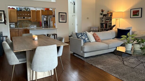 A modern living room with a dining area, a sofa, a coffee table, and a kitchen in the background. - Perfectly located 2-bedroom townhome at The Quail (Carmel)