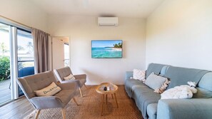 A living room with a sofa, two armchairs, a coffee table, and a painting of a beach scene.
