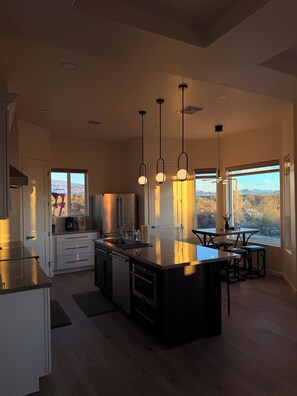A modern kitchen with a central island, pendant lighting, and large windows offering a view of the outdoors. - New Private Desert Escape, Mtn Views with AC in sunny Tucson (Tucson)