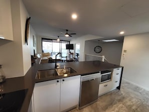 Eine moderne Küche mit Geschirrspüler, Backofen und einer großen Kochinsel mit Spüle.
