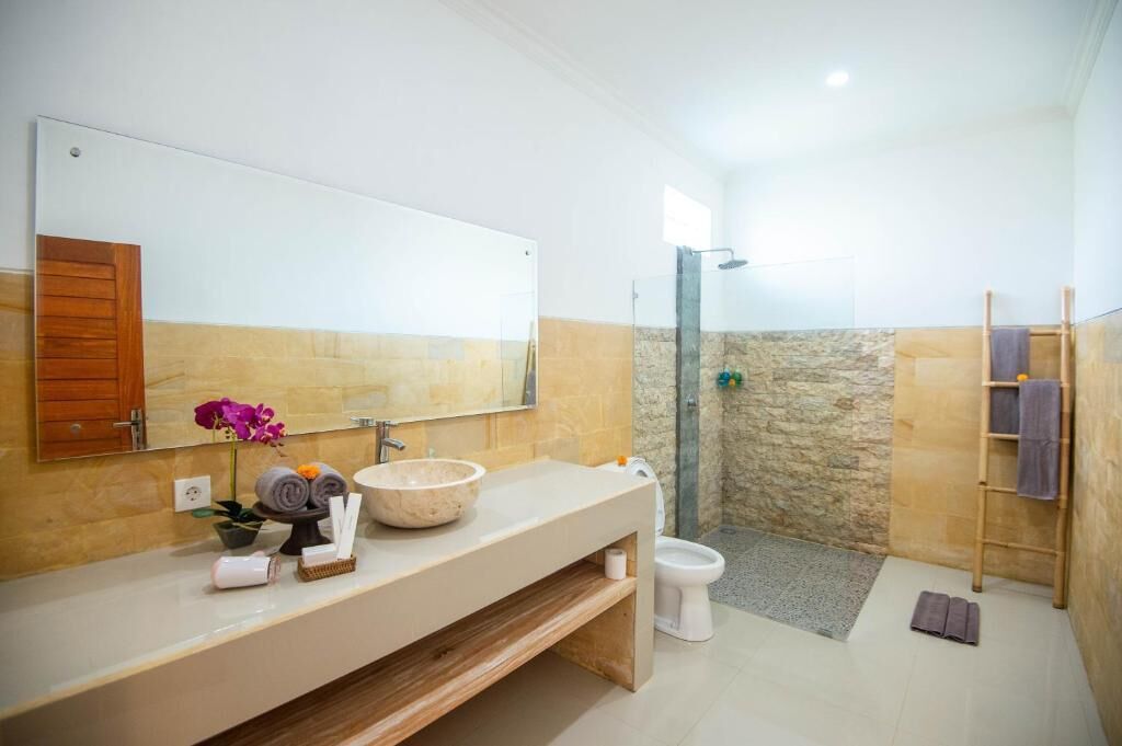 Un baño moderno con un espejo grande, un box de ducha de piedra y un tocador de madera.