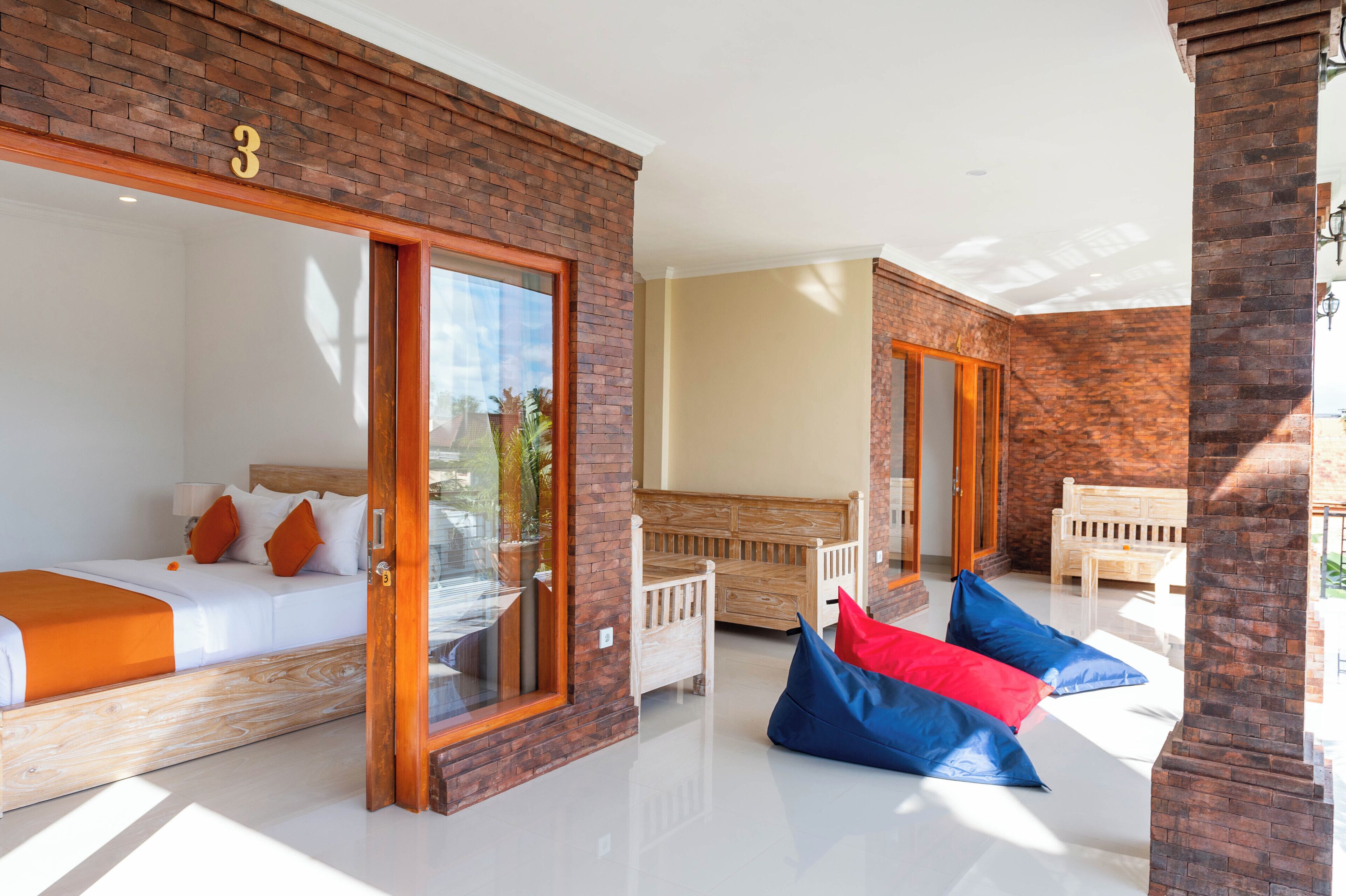 A hotel room with a large bed, a wooden bench, and a seating area with bean bags.