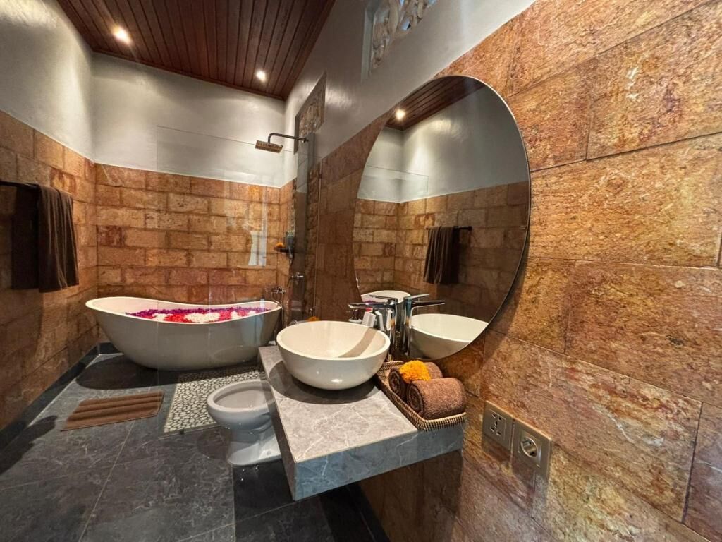 Un baño con bañera, dos lavamanos, ducha y un espejo grande.