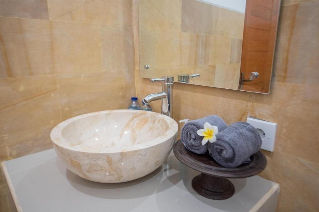 Une salle de bain avec un lavabo en marbre, un porte-serviettes avec des serviettes et un miroir.