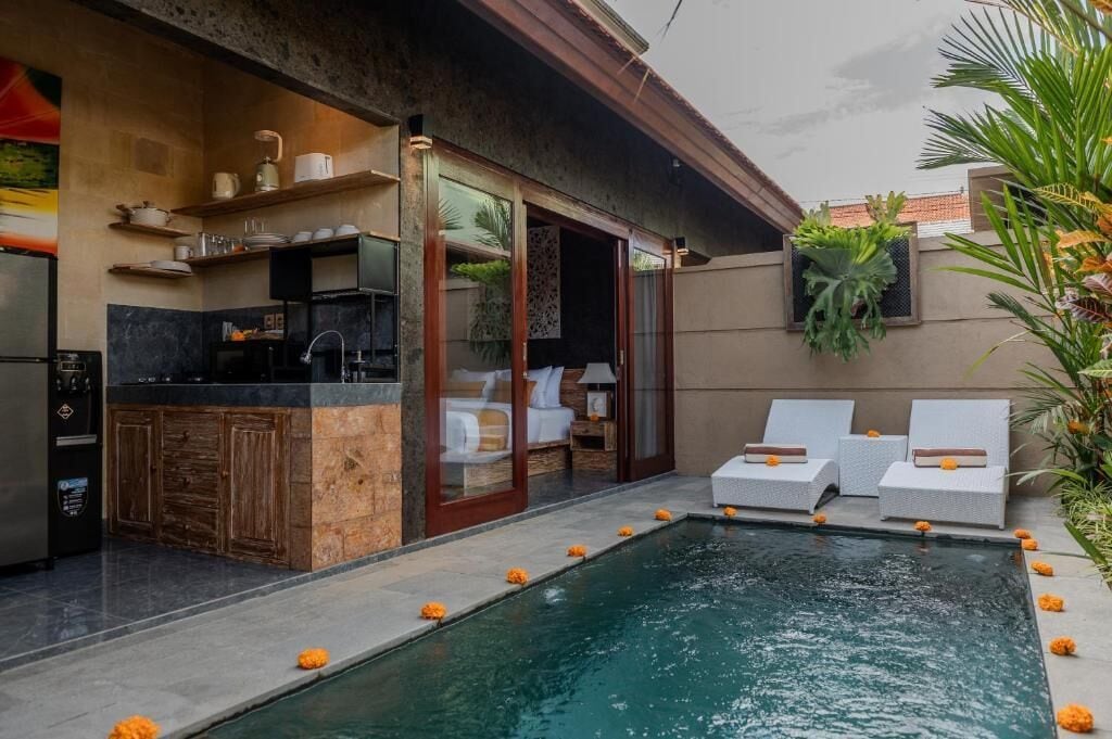Una cocina moderna con estufa integrada, un comedor con mesa y sillas, y una piscina con sillas de descanso.