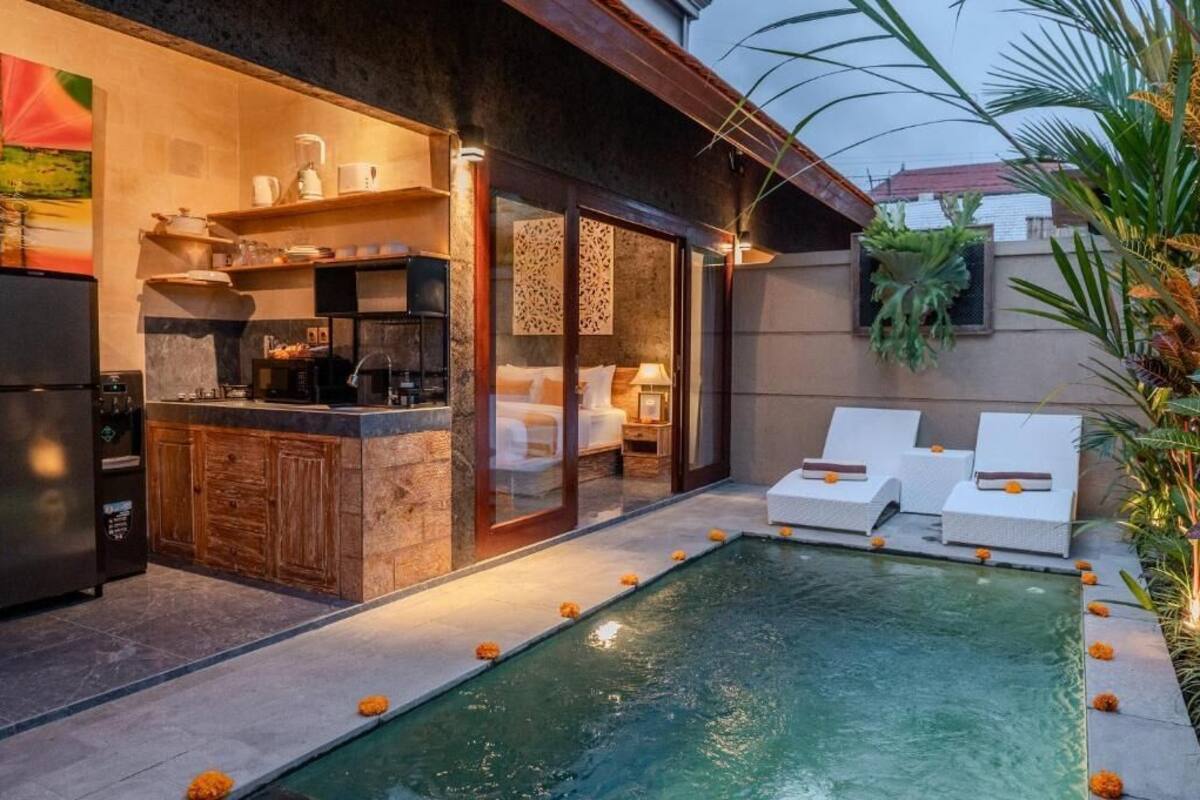 A modern outdoor kitchen with a poolside area, including a bar, seating, and a view of the pool.