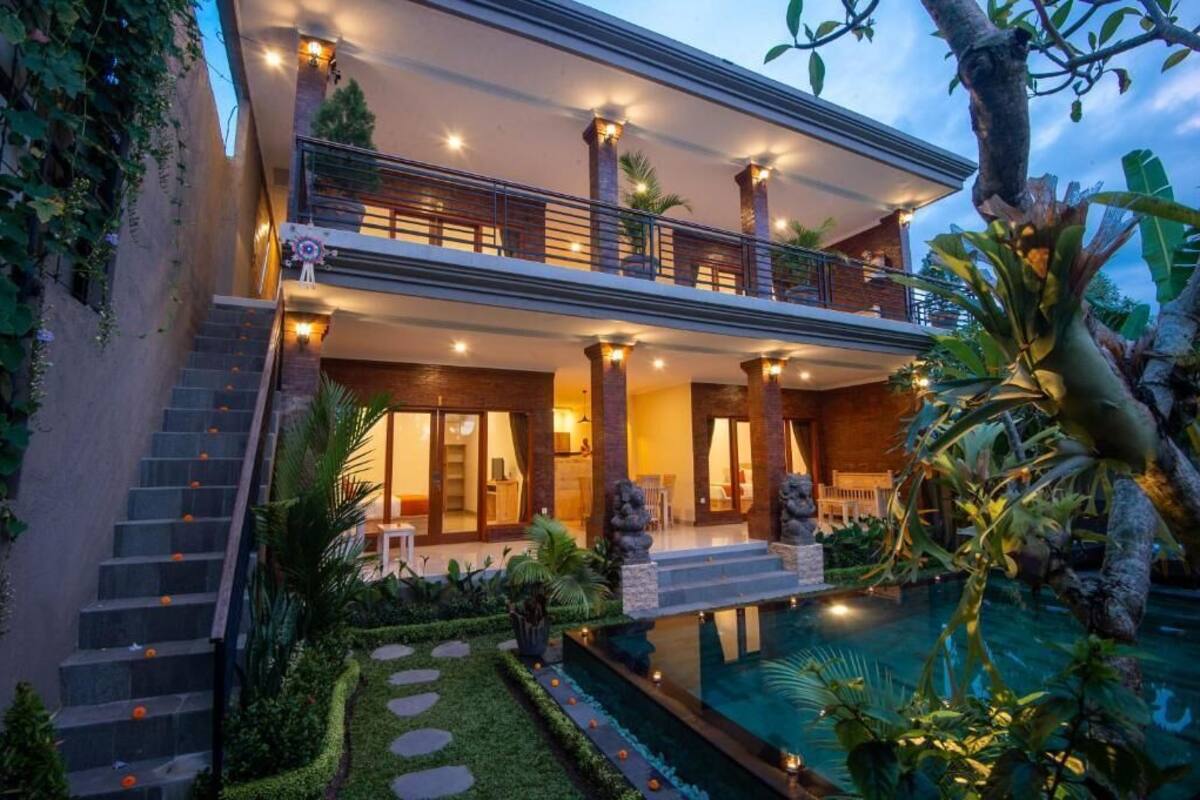 A two-story house with a balcony, a swimming pool, and a well-maintained garden.