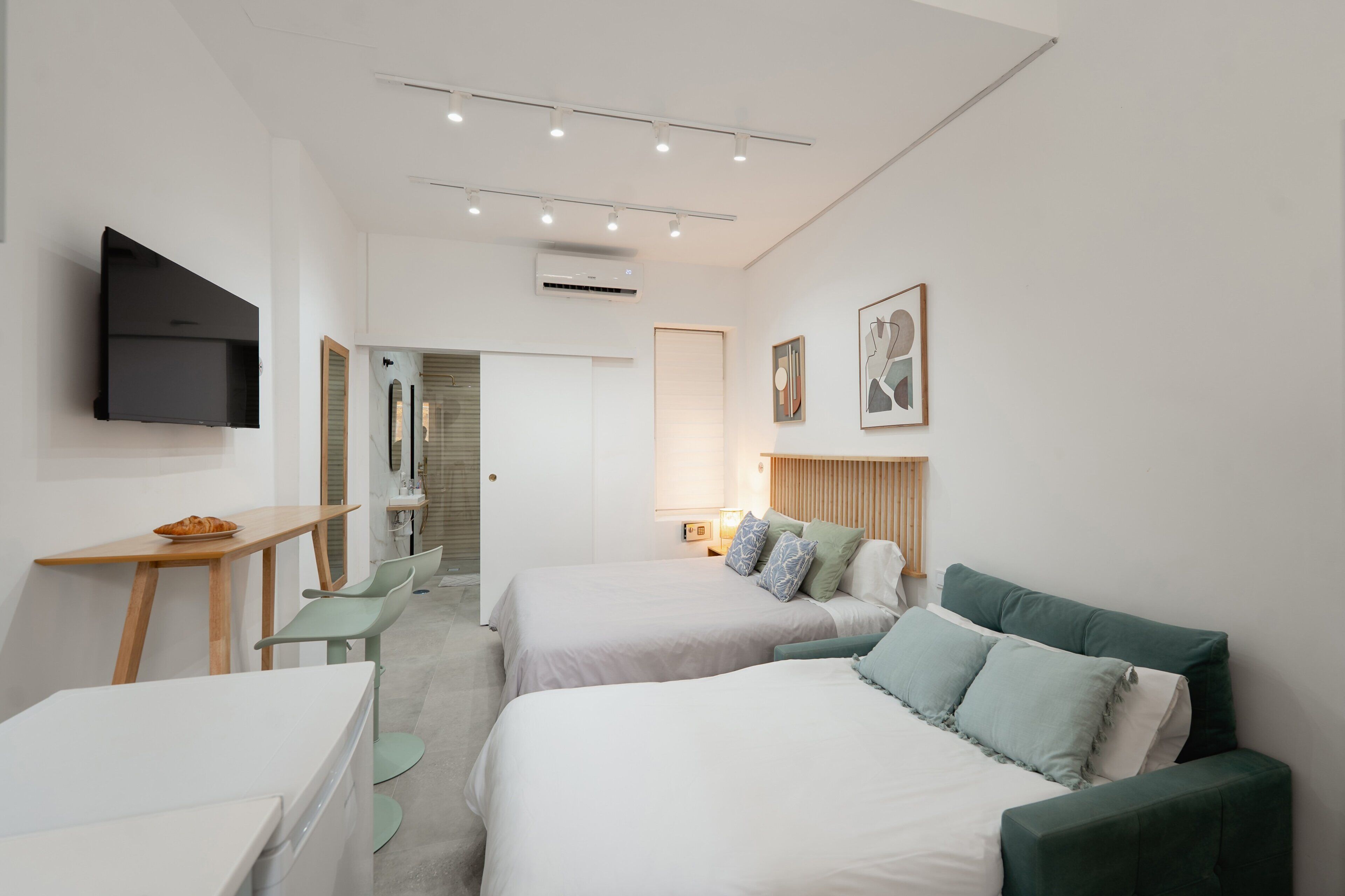 Een moderne hotelkamer met twee bedden, een bureau, een televisie en een badkamer.