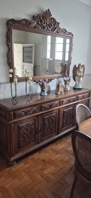 A wooden dresser with ornate carvings, a large mirror, and decorative angel statues. - A complete and cozy house. Close to the historic center and the shopping mall. (São João del Rei)