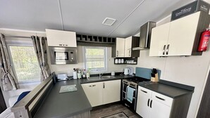 A compact kitchenette with a microwave, stove, and sink. - Forest Retreat Cabin in Ringwood (Ringwood)