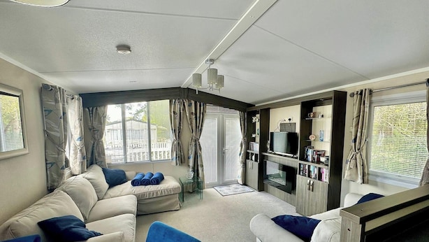 A modern living room with a sofa set, a TV, and a bookshelf. - Forest Retreat Cabin in Ringwood (Ringwood)