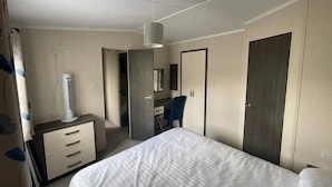 A bedroom with a bed, a dresser, a desk, a chair, a wardrobe, and a hanging light fixture. - Forest Retreat Cabin in Ringwood (Ringwood)