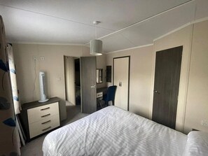 A bedroom with a bed, a dresser, a desk, a chair, a wardrobe, and a hanging light fixture. - Forest Retreat Cabin in Ringwood (Ringwood)