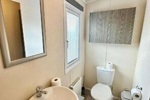 Ein Badezimmer mit Waschbecken, Toilette und Spiegel.