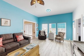 Ein Wohnzimmer mit blauer Wand, einem braunen Ledersofa, einem gemusterten Sessel und einem Holztisch.