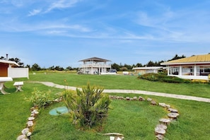 A residential property with a large lawn, a small pond, and a covered outdoor area. - Coastal pool view condo with shared hot tub & beach trail access, dog-friendly (Copalis Beach)