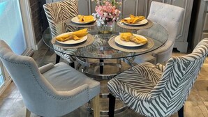 Et rundt glastbord med stolte betrukket med zebraprint, en lysekrone og en dekorativ væg.