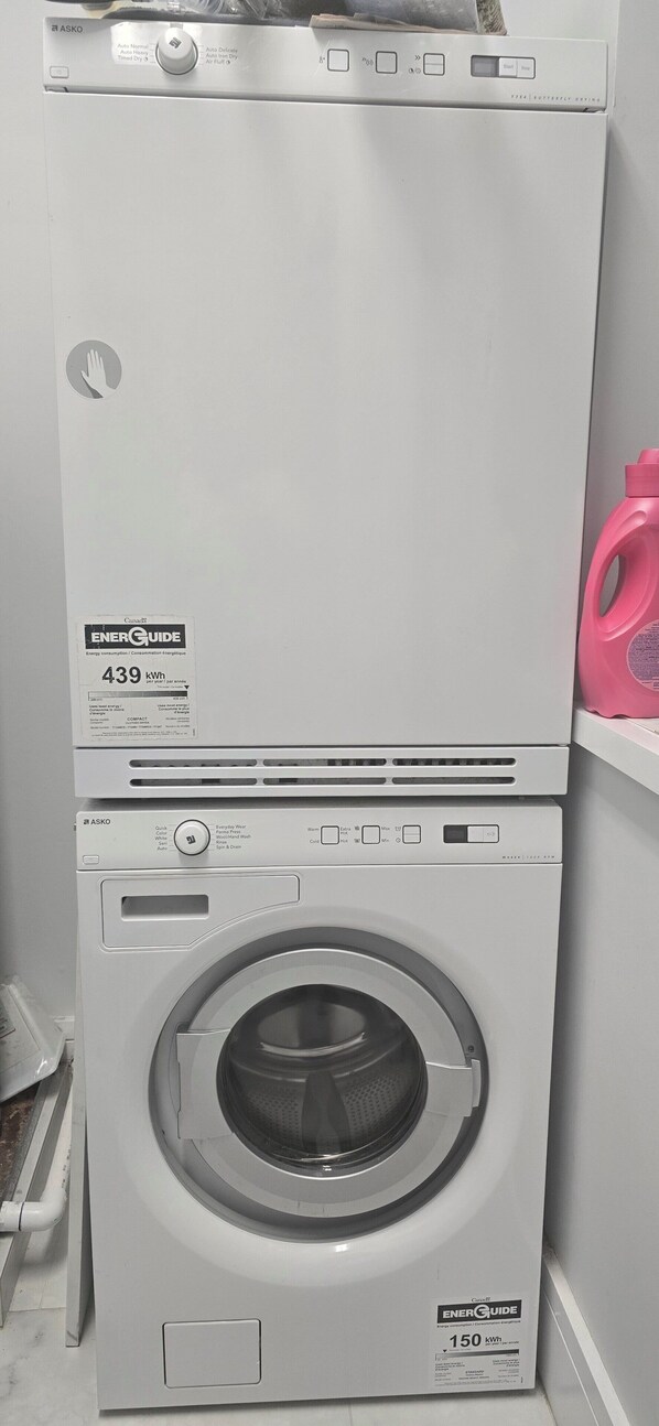 Un appareil combiné lave-linge et sèche-linge compact, doté d’une étiquette « Guide énergétique » indiquant une consommation de 439 kWh pour le lavage et de 150 kWh pour le séchage.