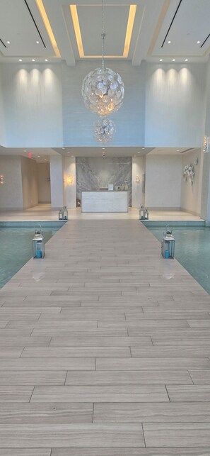 A spacious indoor pool area with a reception desk, a large chandelier, and two lantern-style lights. - Paradise at one cable beach (Nassau)