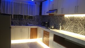 A modern kitchen with white cabinets, a tiled backsplash, and under-cabinet lighting.