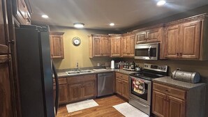 A kitchen with wooden cabinets, a refrigerator, a microwave, an oven, and a sink. - Luxury Golf Course Chalet Near World Cup Matches Airport and Legends, Sleeps 6+ (Basehor)