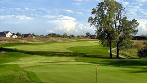 A golf course with a flagstick, trees, and houses in the background. - Luxury Golf Course Chalet Near World Cup Matches Airport and Legends, Sleeps 6+ (Basehor)