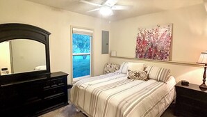 A bedroom with a bed, dresser, ceiling fan, window, and artwork. - Luxury Golf Course Chalet Near World Cup Matches Airport and Legends, Sleeps 6+ (Basehor)