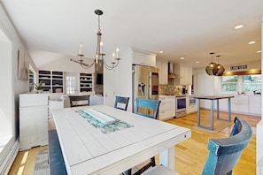 A modern kitchen with white cabinetry, a dining area with a white table, and a chandelier. - Stunning home with amazing views, a private pool, serenity & lake access (Meredith)