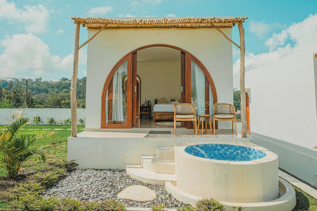 A private villa with a bedroom, a sitting area with chairs, and a swimming pool.