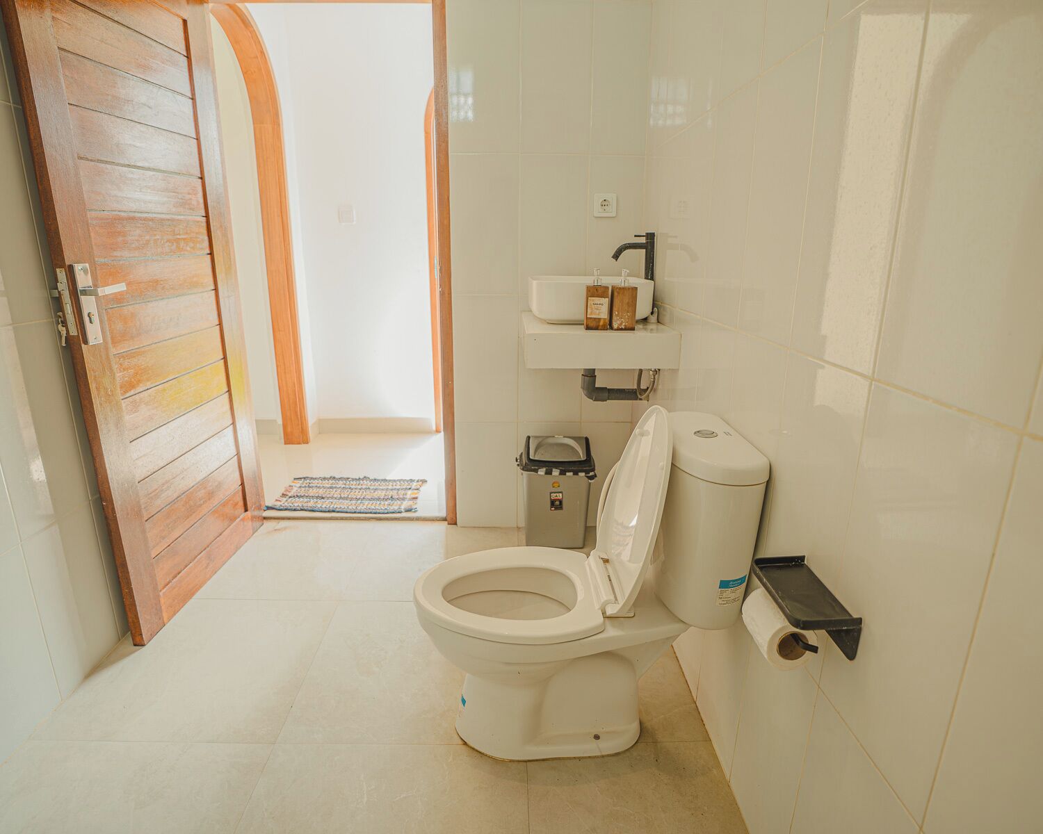 Une salle de bain comprenant des toilettes, un lavabo, une poubelle et un espace douche.
