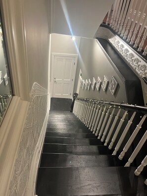 A staircase with a handrail, a door at the top, and wall-mounted pictures. - Perfect family-friendly 5-bedroom home in historic downtown Jersey City FIFA (Jersey City)
