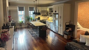 Una cocina amplia con una isla grande, armarios blancos y una pared decorativa de ladrillo.