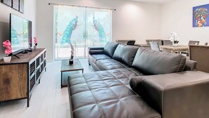 Een moderne woonkamer met een leren bank, een houten salontafel en een televisie op een houten dressoir.