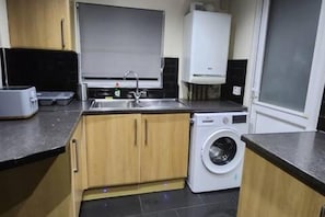 A compact kitchen with a sink, a washing machine, and a toaster.