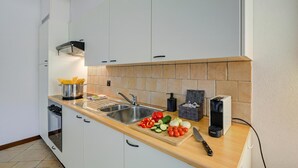 A modern kitchen with white cabinets, a wooden countertop, a sink, and a coffee machine. - Historic Palazzo Gritti - Lugano Lakefront stay - Fiordaliso, Morcote, Switzerland (Morcote)
