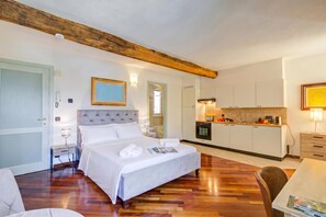A hotel room with a bed, bedside tables, a small kitchenette, and a wooden ceiling beam. - Historic Palazzo Gritti - Lugano Lakefront stay - Fiordaliso, Morcote, Switzerland (Morcote)