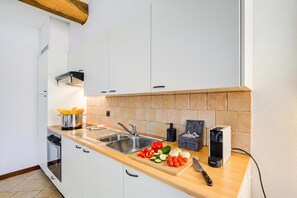 Una cocina moderna con armarios blancos, encimera de madera, horno empotrado y un lavamanos.