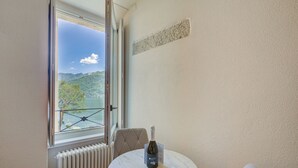 A room with a view of a lake, a table with a bottle, a chair, and a radiator. - Historic Palazzo Gritti - Lugano Lakefront stay - Fiordaliso, Morcote, Switzerland (Morcote)