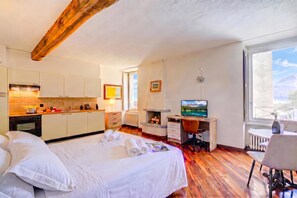 Habitación de hotel con cama, escritorio con computadora, una mesita y ventana con vistas.