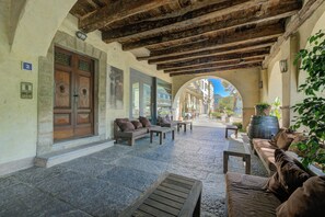 An outdoor seating area with stone flooring, wooden furniture, and a view through an archway. - Palazzo Gritti Camelia, Morcote, Switzerland (Morcote)