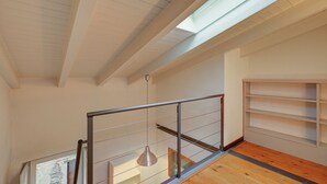 Un interno moderno con pavimento in legno, ringhiera in metallo e un lucernario.