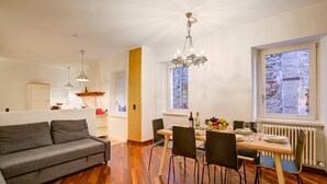 Zona pranzo con tavolo apparecchiato per quattro persone, un lampadario e vista dalla finestra.