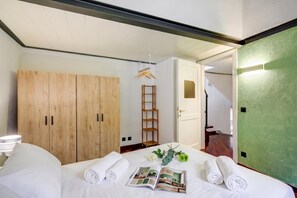 A neatly made bed with rolled towels, a magazine, and a small plant. There is a wooden wardrobe and a ladder against the wall. - Palazzo Gritti Camelia, Morcote, Switzerland (Morcote)