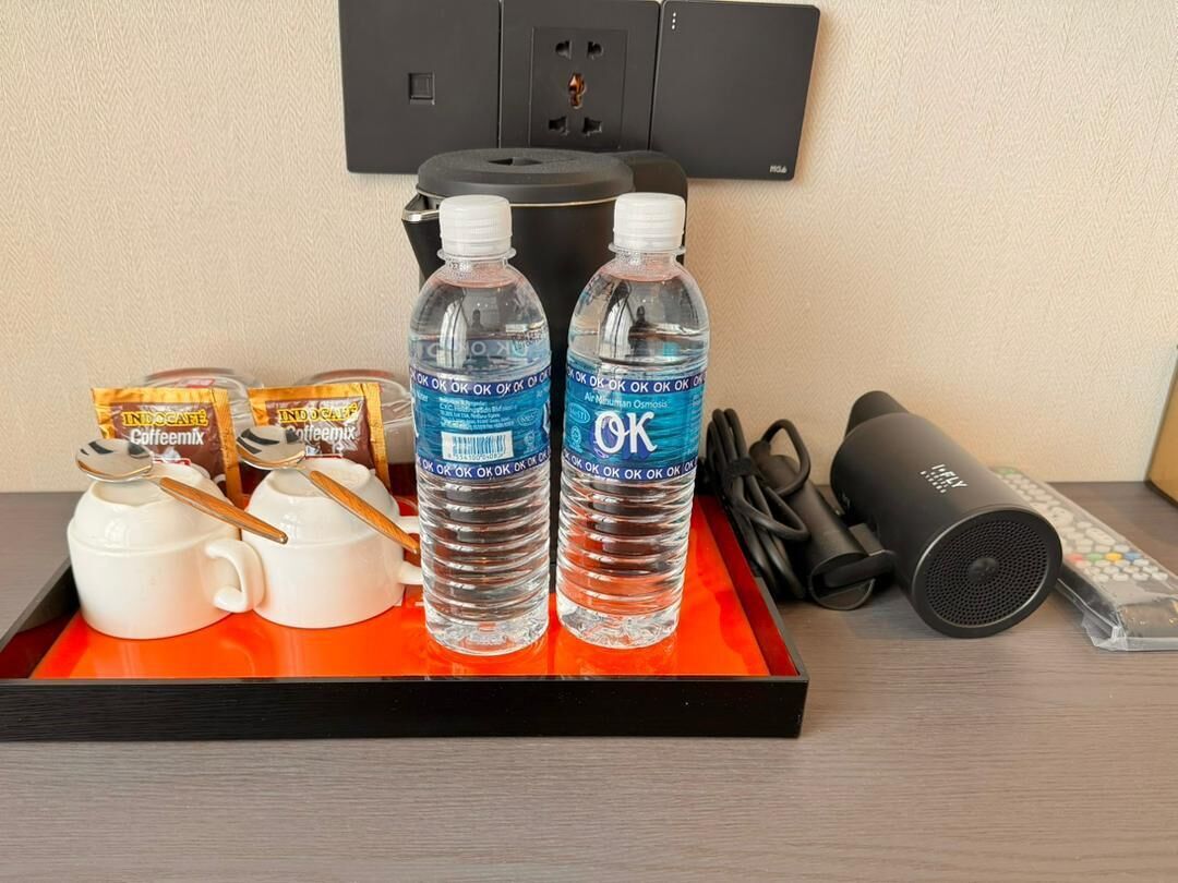 Un plateau avec deux bouteilles d’eau, une machine à café, une télécommande et une paire d’écouteurs.