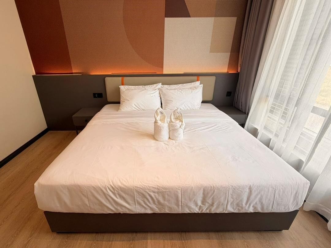 Un letto rifatto con una coperta bianca e due paia di scarpe sopra.