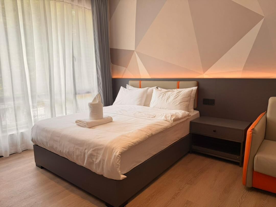 Una habitación de hotel moderna con cama, mesita de noche y una silla.