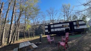 Ein Campingplatz mit einem Wohnmobil, einem Picknicktisch und zwei Stühlen.